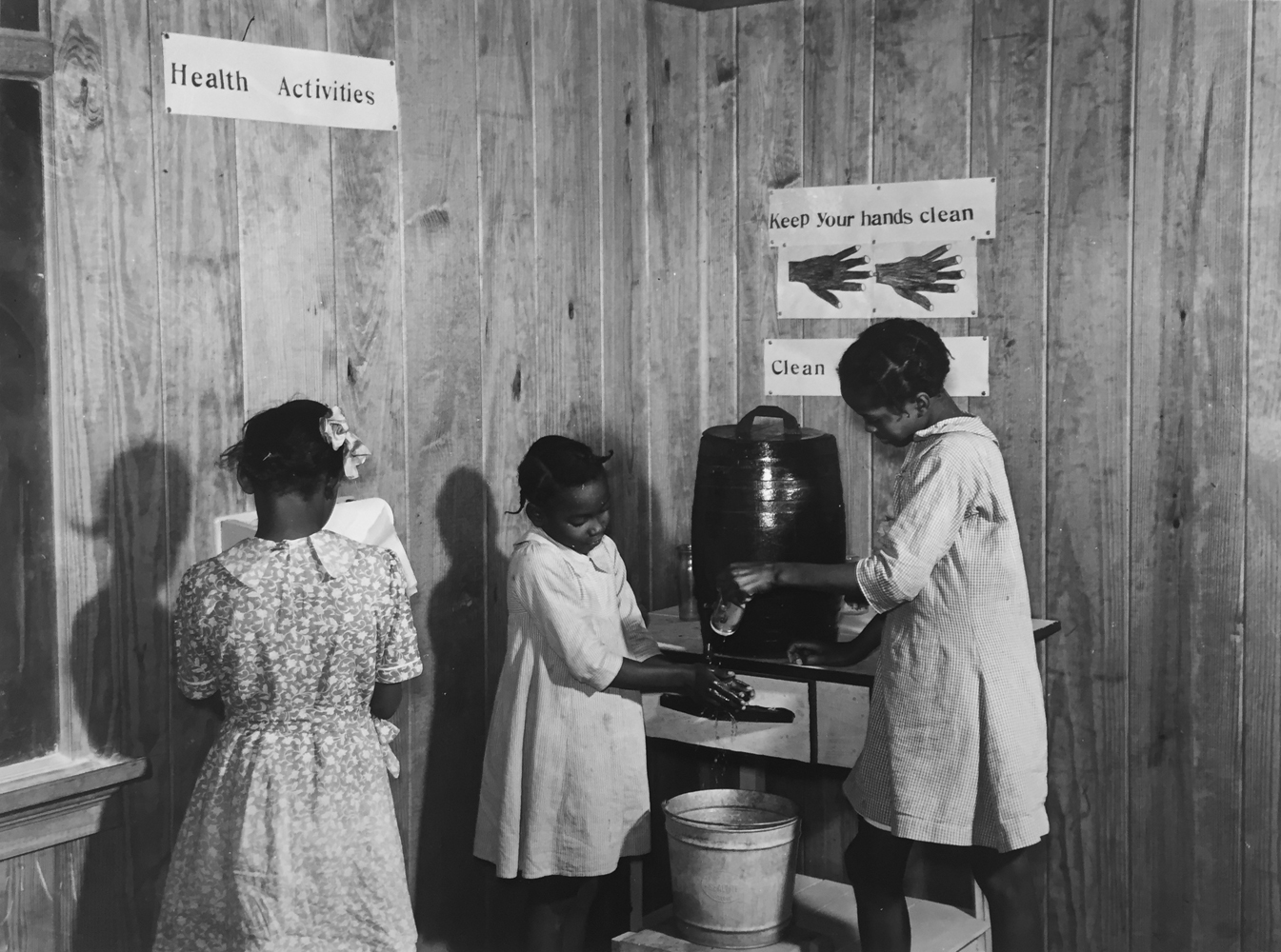 Marion Post Wolcott, Gladys Crimer drying her hands on a paper towel and Berenice Mathis and Edna Law washing theirs in the cleanup corner in the second- and thirtd-grade schoolroom, near Montezuma, Georgia, 1939, gelatin silver print, 11 x 14 inches, signed by artist, $3000.